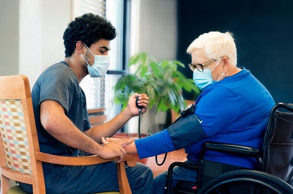 A CNA checking patient's blood pressure